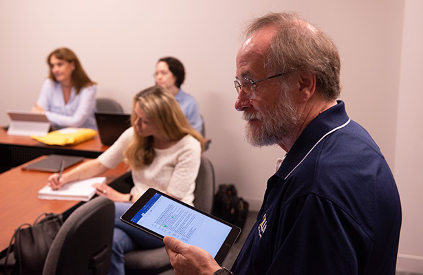 Male professor in class holding tablet in his hand