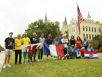 International students stand in front of OLLU with different flags